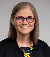 Woman with glasses smiling.
