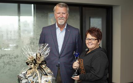 UFG President and CEO Randy Ramlo stands to the left of 2021 Go Beyond winner Kelly Thomas who holds the silver and blue trophy.