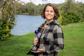 Woman holding a trophy outside.