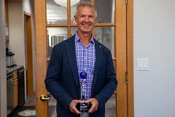 2024 Agent Go Beyond1-UFGNews Man smiling and holding trophy.