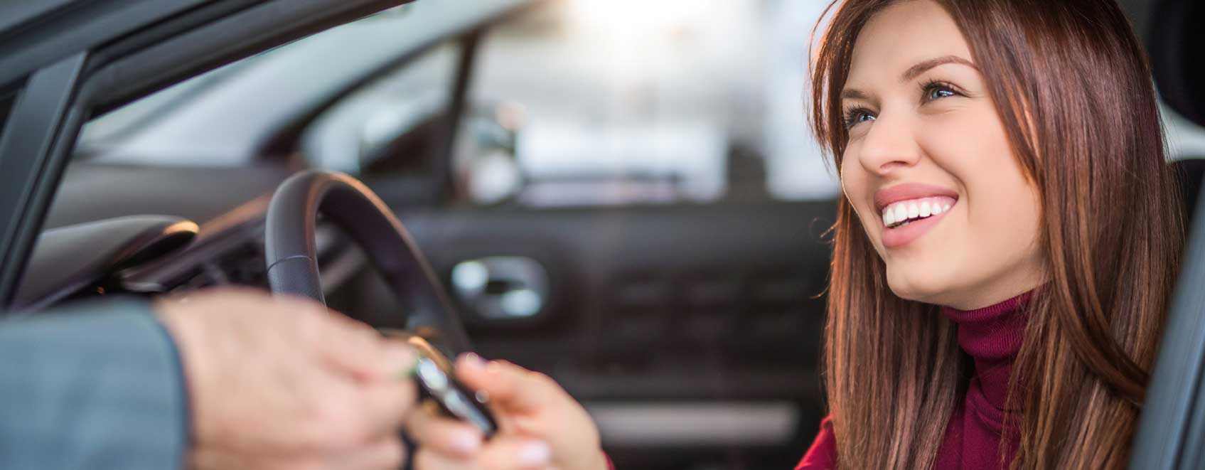 person handing a set of keys to a driver sitting in their car