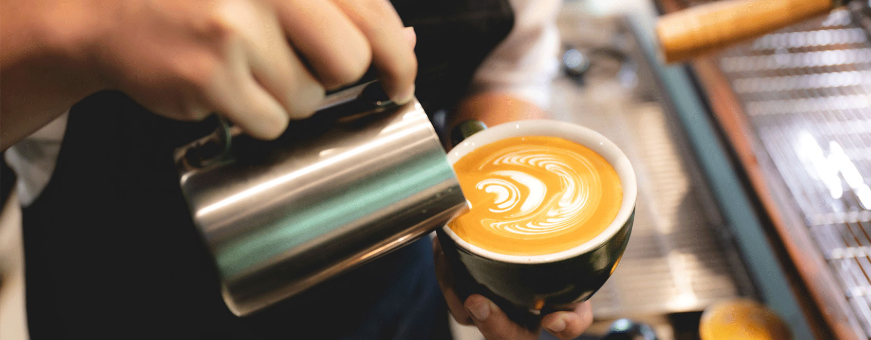 Barista pouring into a coffee mug. 