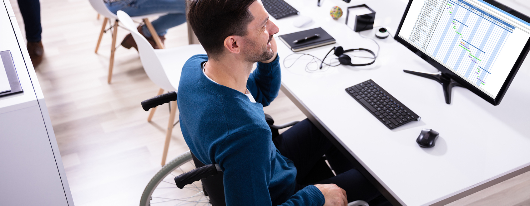 person in wheelchair, talking on phone at computer station