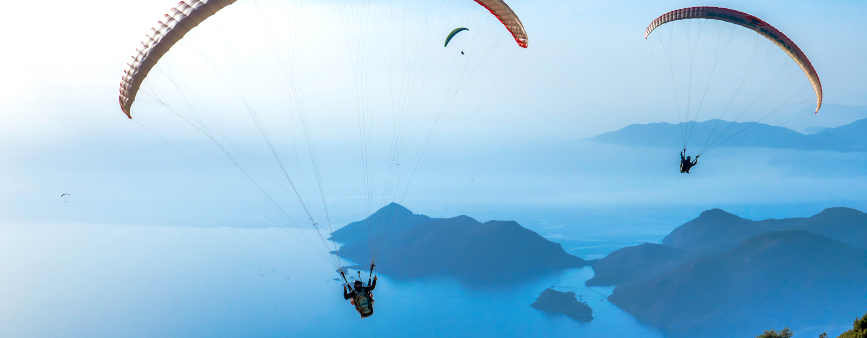 three persons parasailing in sky