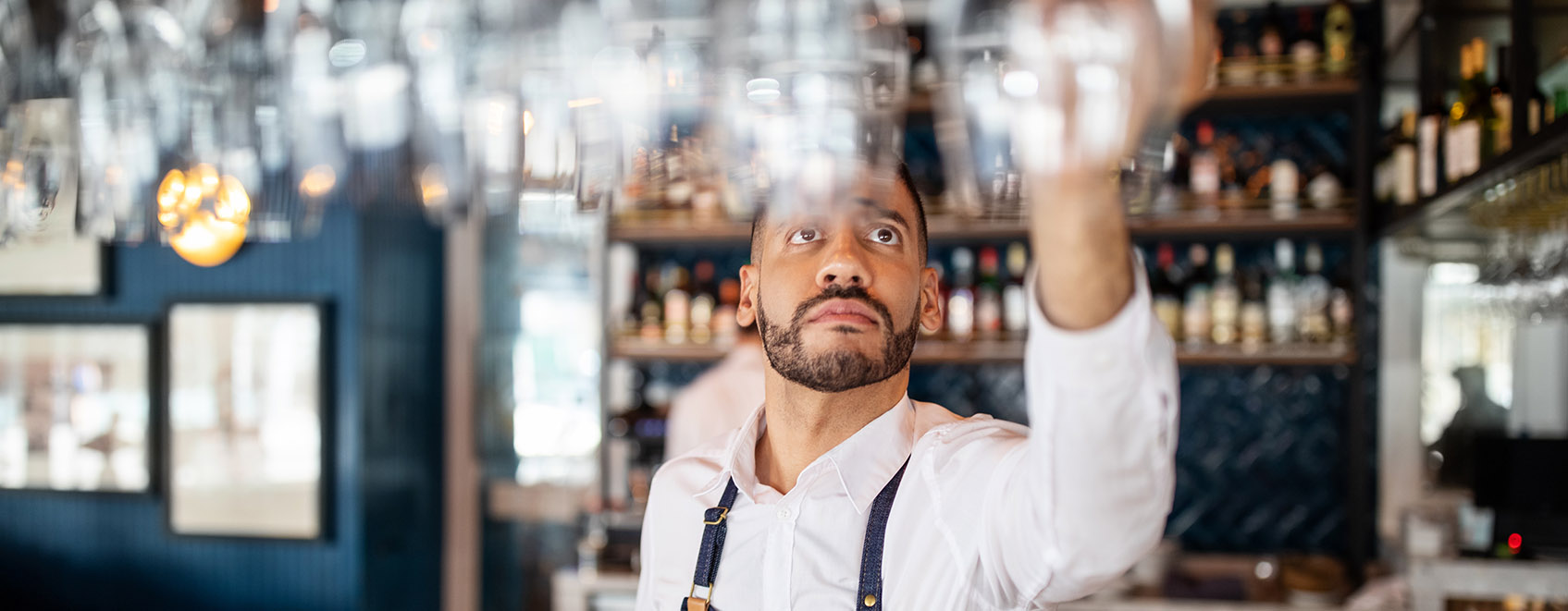 Bartender hanging wine glasses above the bar.