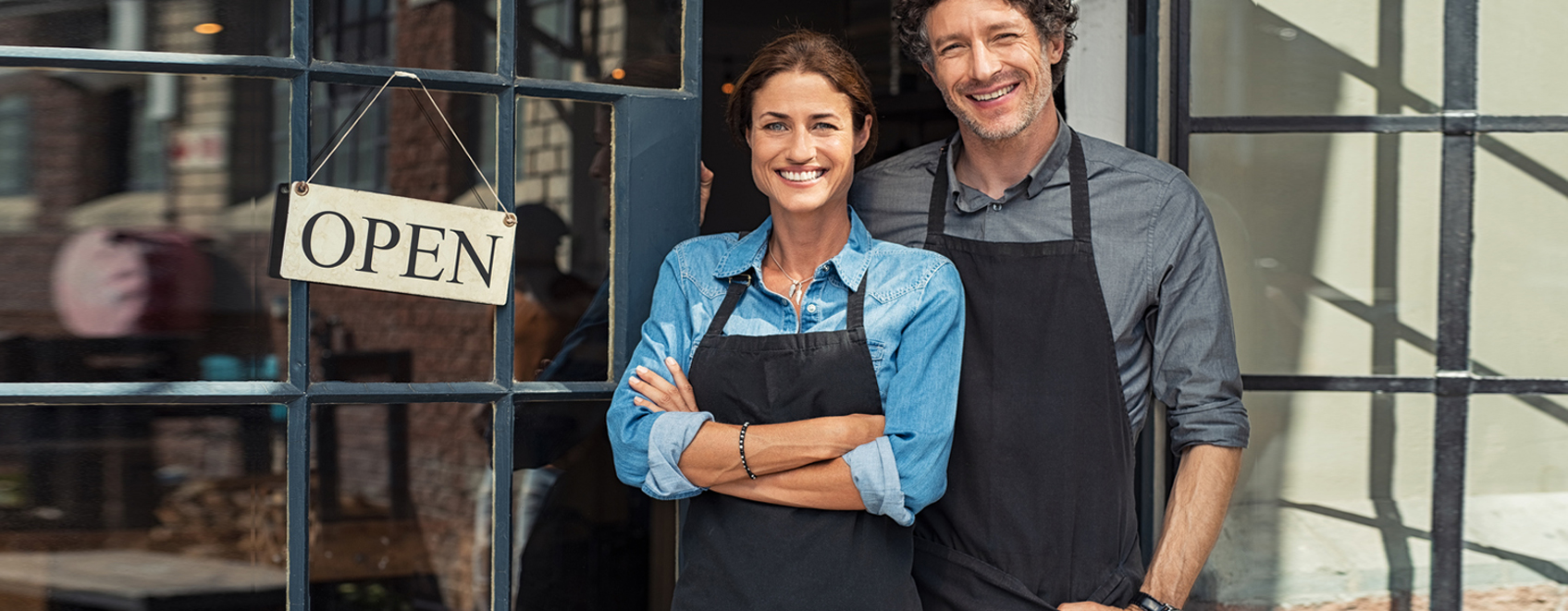 two business owners smiling next to Open sign