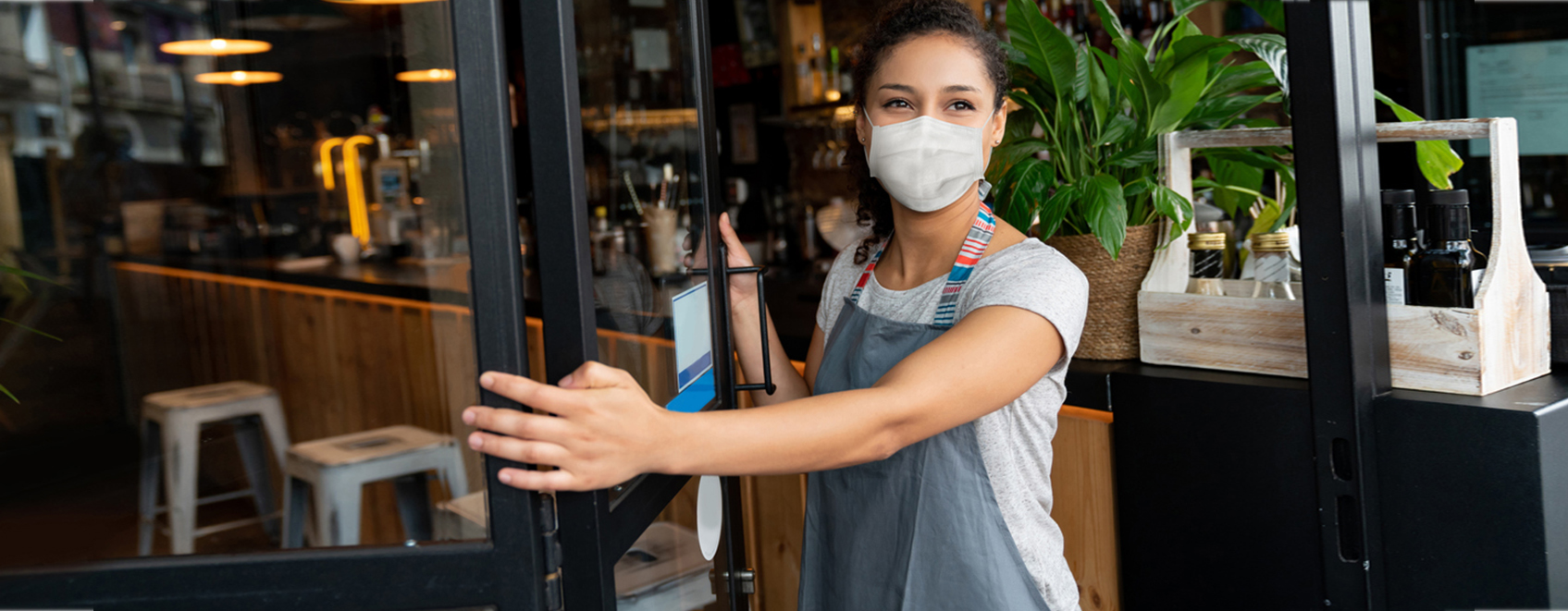 business owner in mask, opening front door of cafe