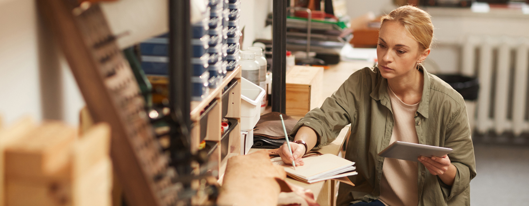 Small business owner at work bench, with tablet and notepad