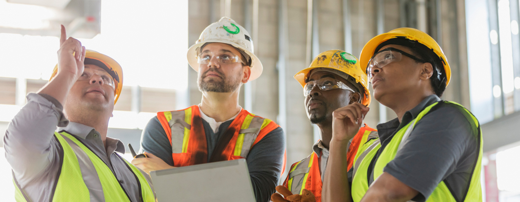 Group of workers at a construction site with hard hats and reflective vests.