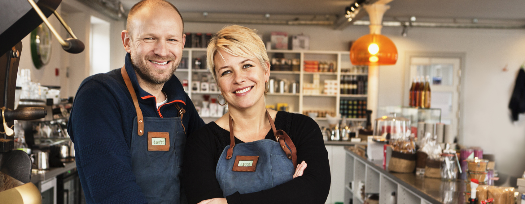 Owners stand smiling in their small business