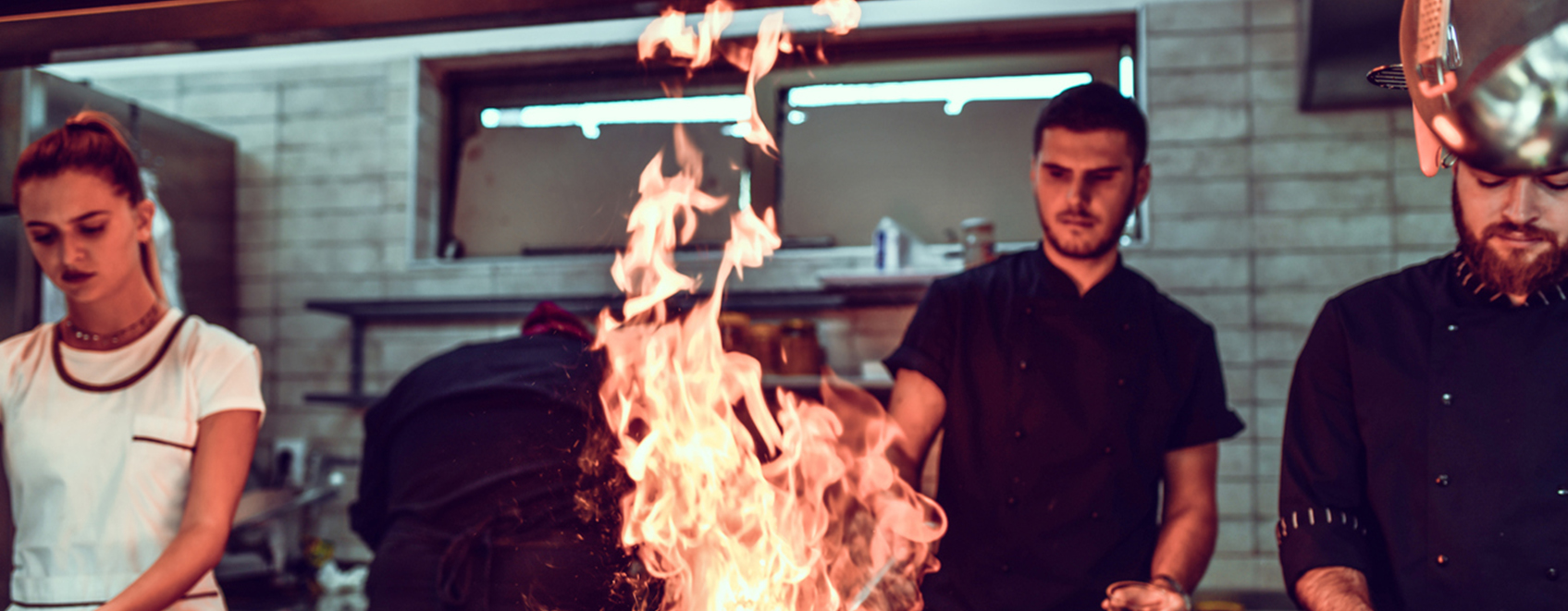 Restaurant chef cooking with flame in pan.