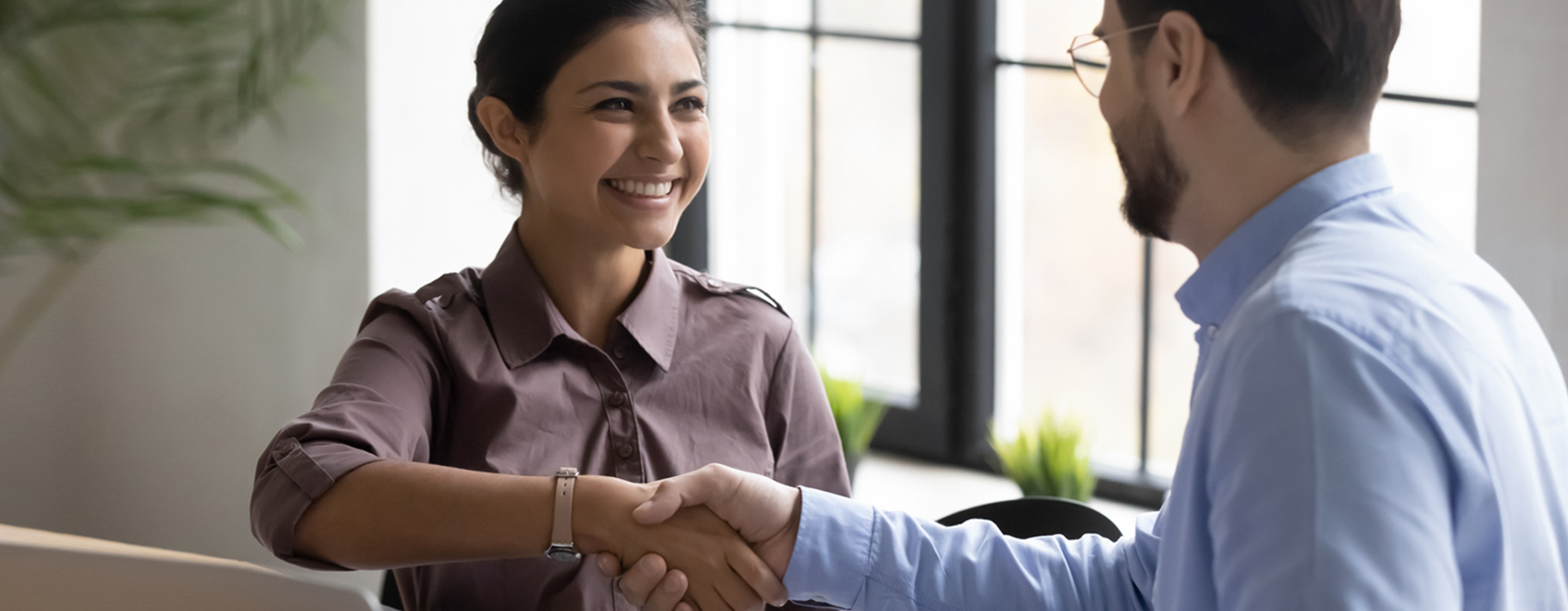 Two business people shaking hands and smiling. 