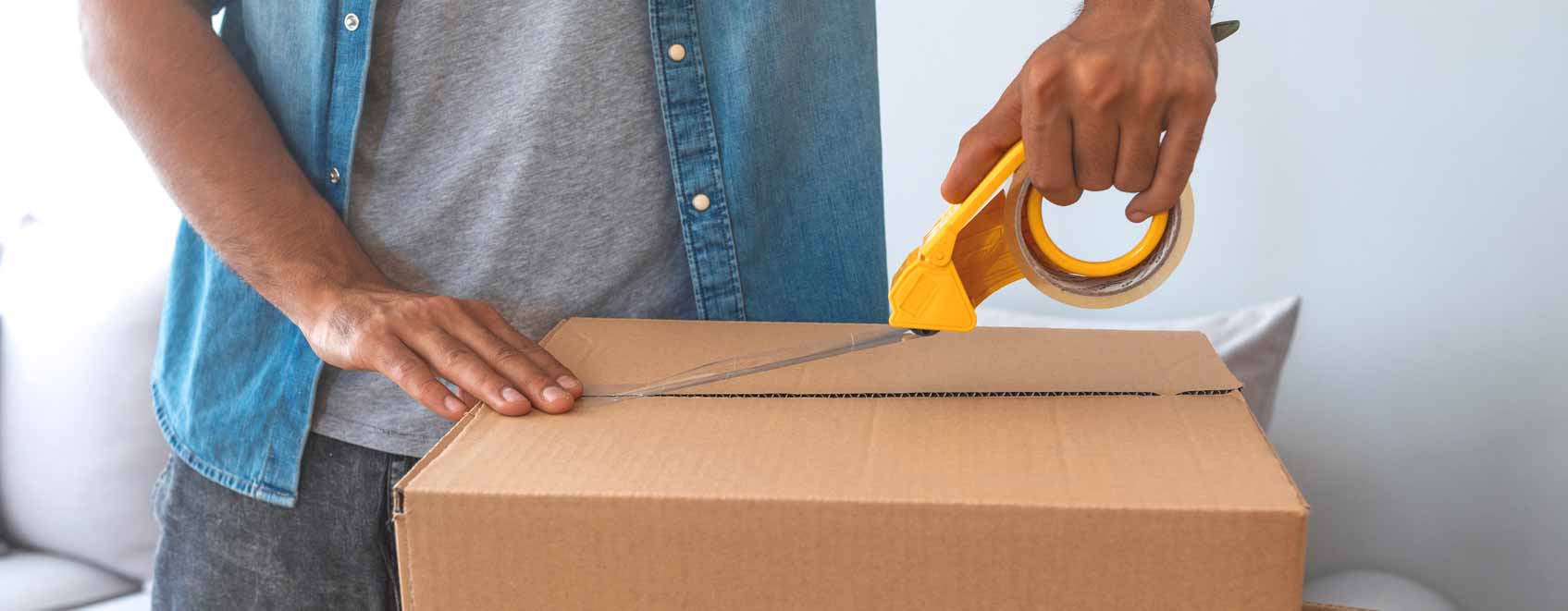 Person taping moving boxes together. 