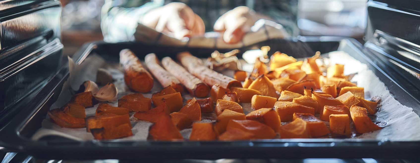 Assorted vegetables on baking sheet cooking in oven.