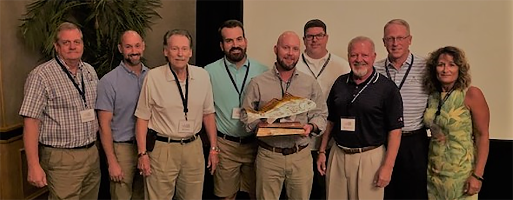 UFG Gulf Coast Regional Office employees smiling for a picture with their Outstanding Core Carrier award.